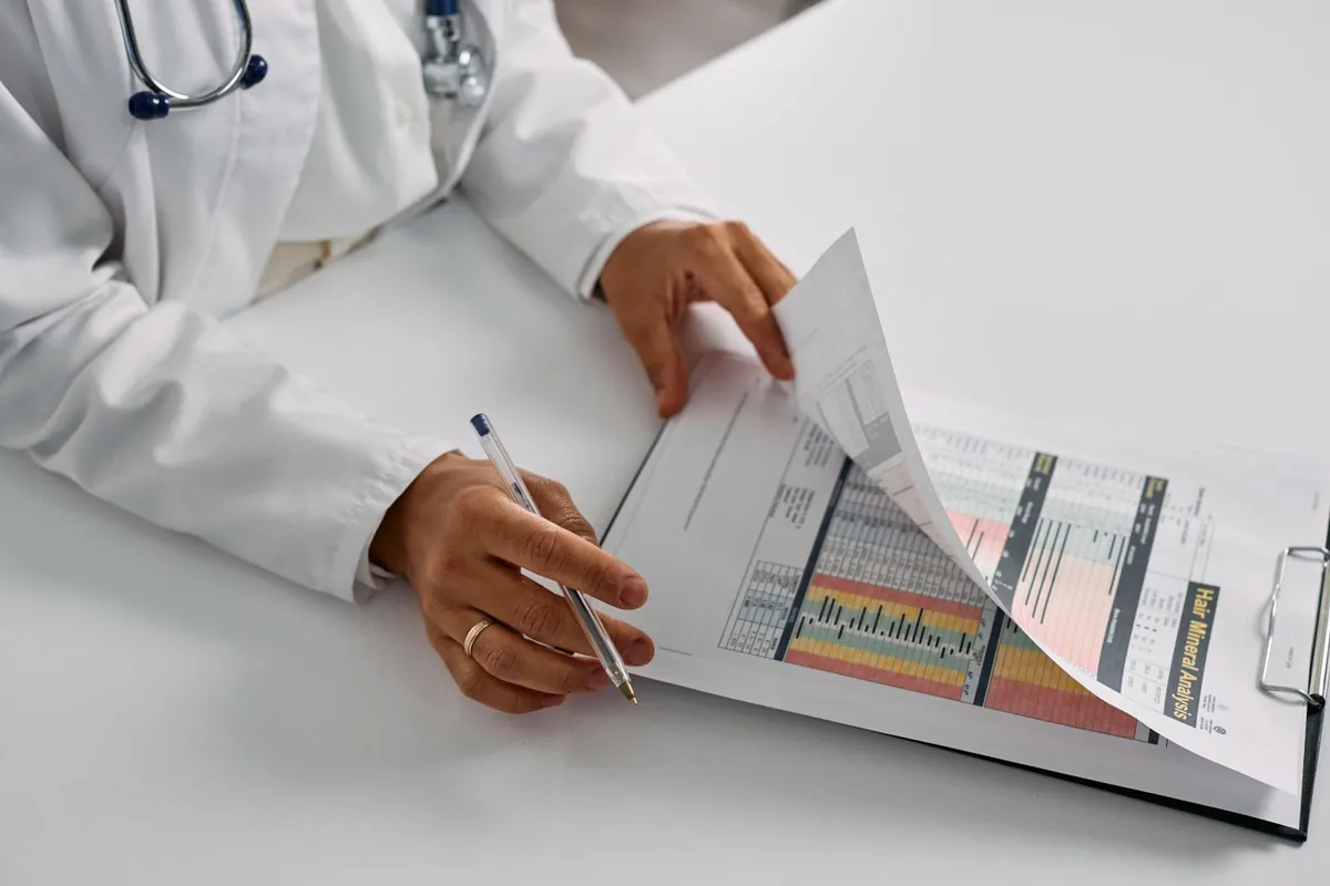 Hands of a medical professional reviewing documents on a clipboard