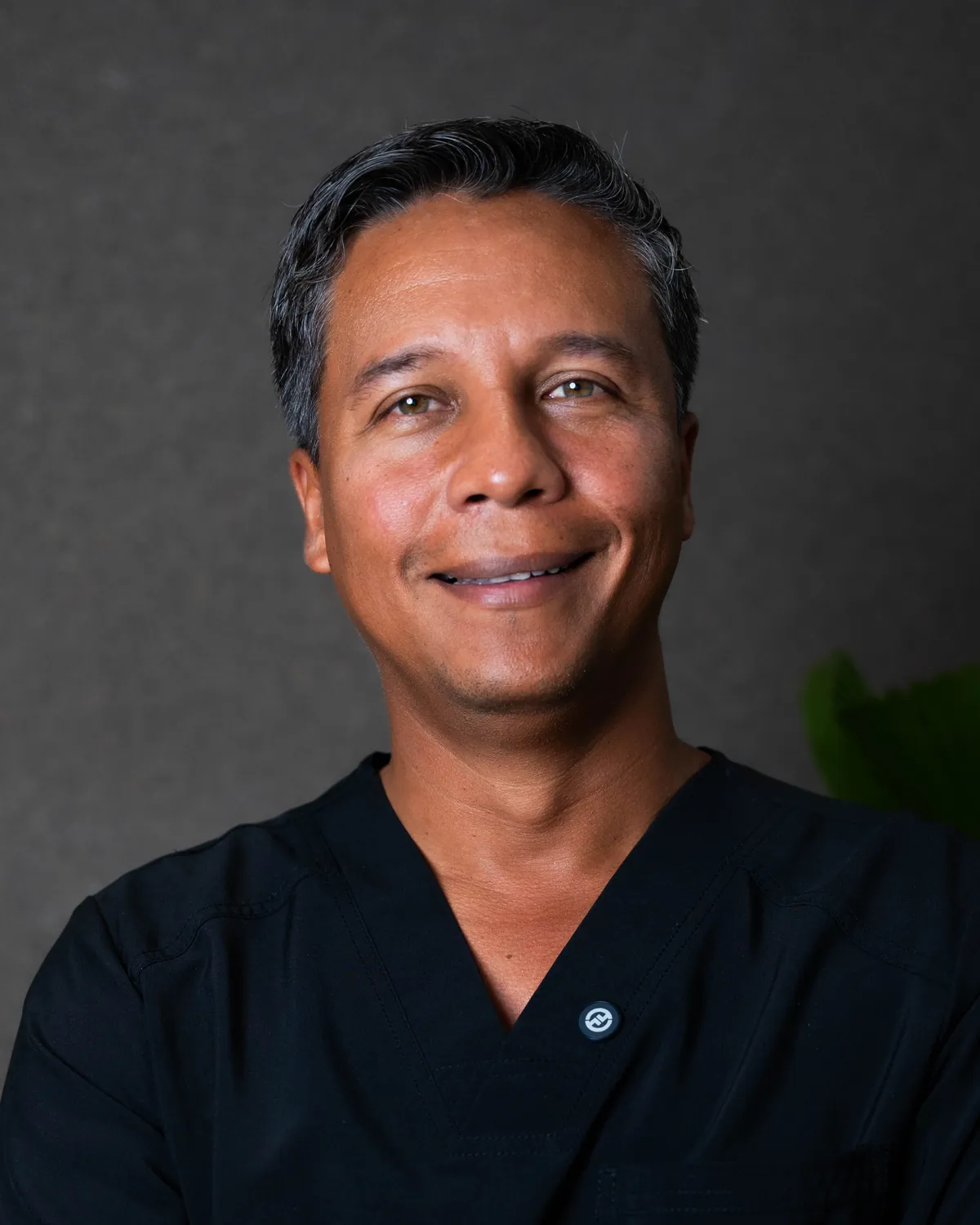 Dr. Fulvio Correa, plastic surgeon in Cartagena, Colombia, smiling in black scrubs